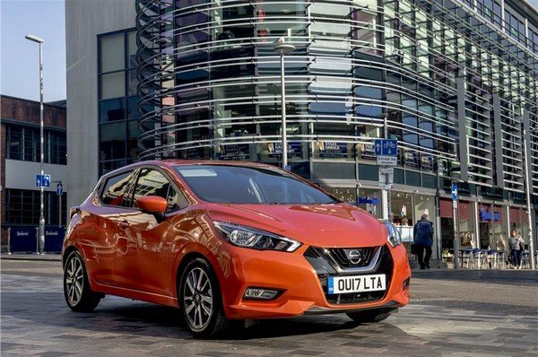 Orange 2018 Nissan Micra parking on road, angular left side view, background of buildings