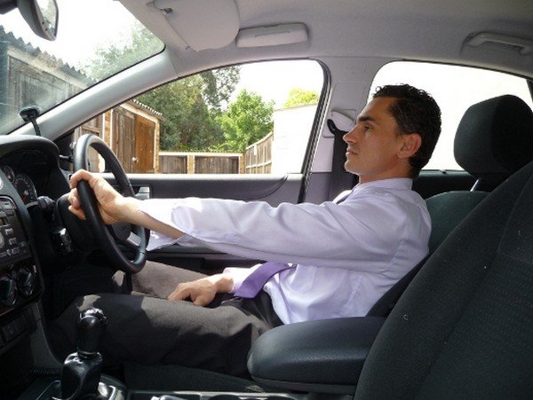 sideways view of male driver behind the driving wheel