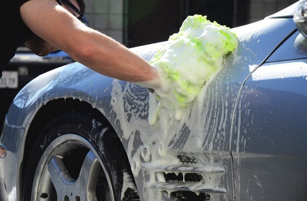 car being washed with soap, man using green wash mitt