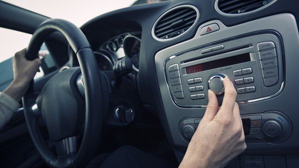A hand turning on the radio inside a car