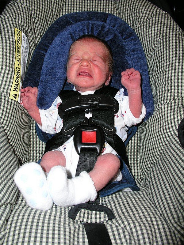 A baby sitting in infant car seat crying