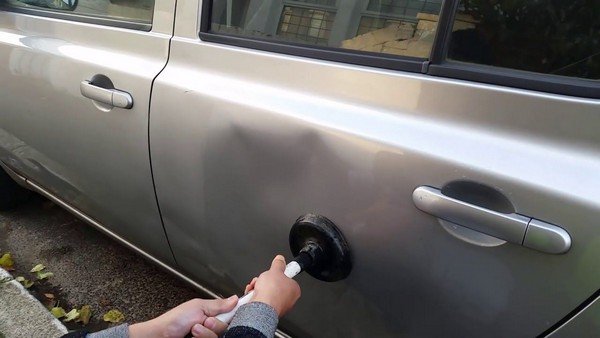 Someone using a plunger to erase the dents on the car