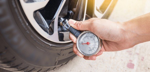 Someone using a pressure gauge to check the tyre pressure