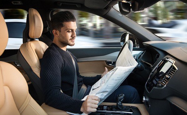 A man reading newspaper when the car drives him to work