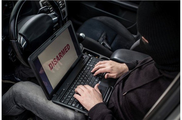 A thief using a laptop to hack a car