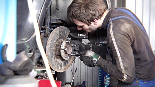 man-repairing-old-car-braking-system