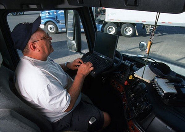 man driving while typing on laptop