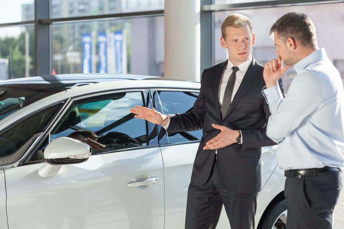 a car salesman introduces a car to customer
