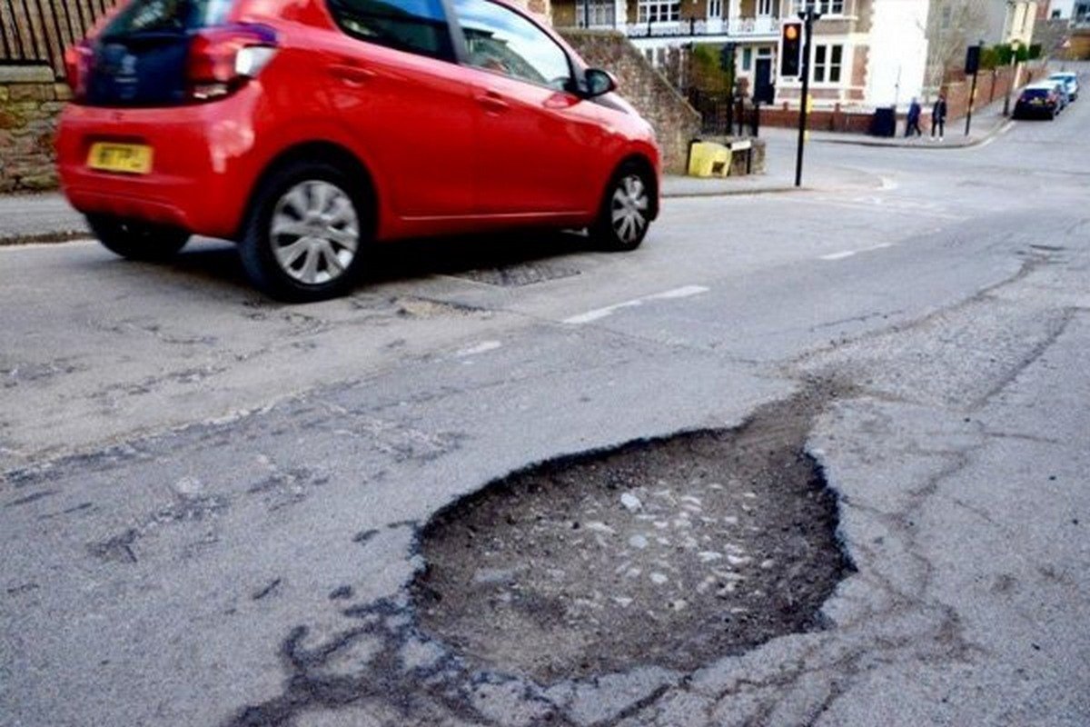 A red car and a pothole