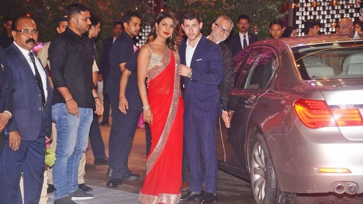 Priyanka Chopra and Nick Jonas standing next to the BMW 5-Series