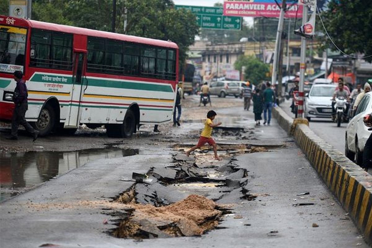 a boy crossing potholes in India