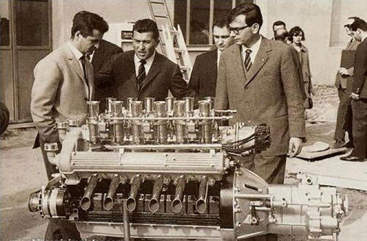 Lamborghini and 2 other men checking out an engine