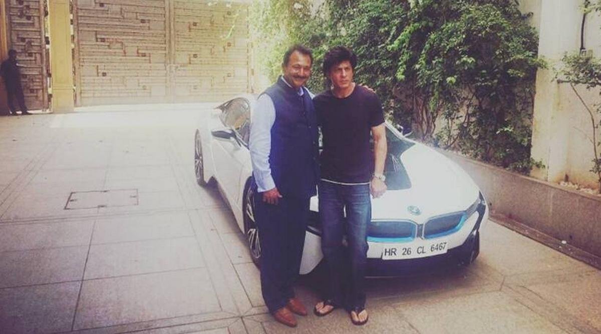 Shahrukh Khan standing next to his white hybrid BMW i8