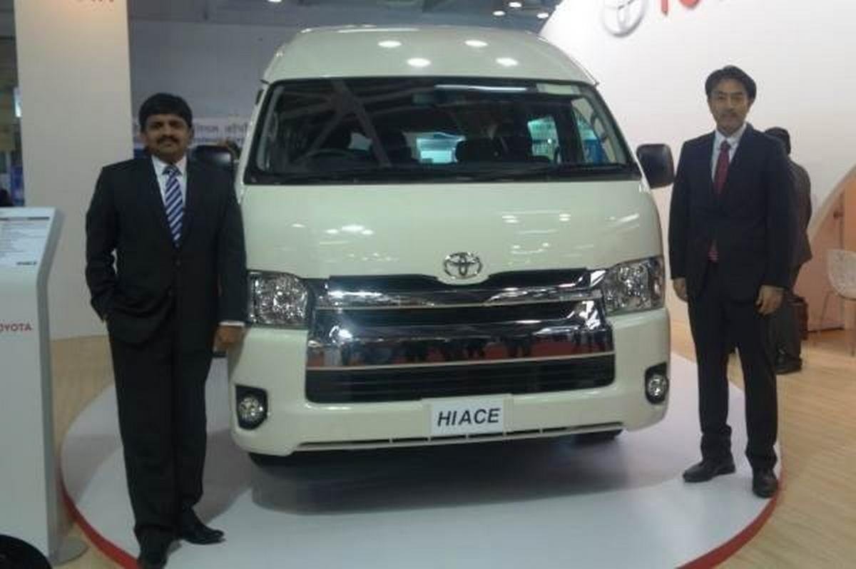 Toyota Hiace pickup truck white front between two men