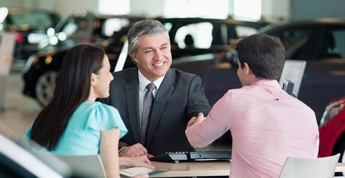 a car salesman hands shaking with two customers