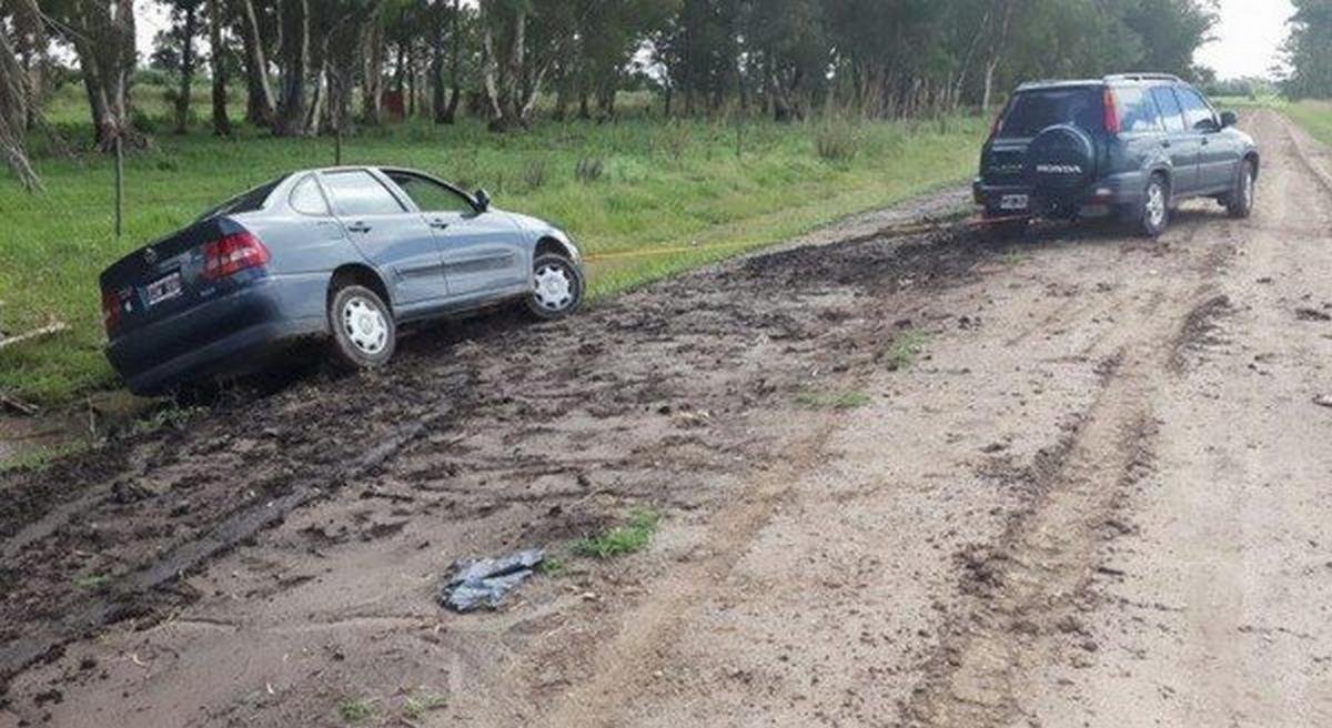 A hatchback car is pulling another car out of the mud