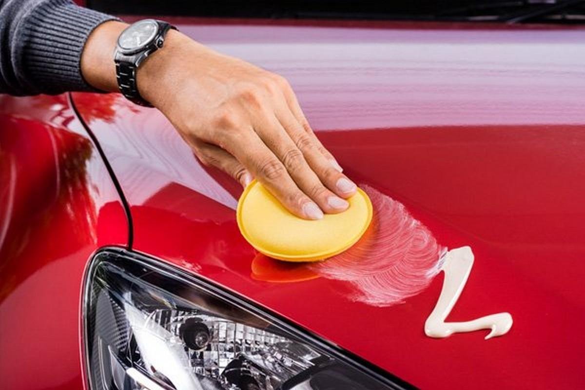 a hand is waxing a red car