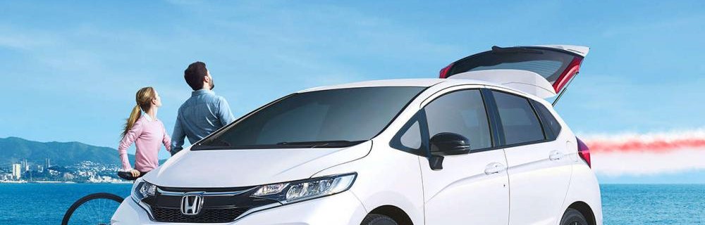 Honda Jazz 2018 white colour park on road front look open trunk sky and ocean background